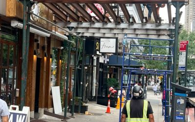 1411 2nd Ave Manhattan Sidewalk Shed Steel Beam Installation — Worker installing steel I-beam framing for new sidewalk shed structure, crew member o