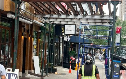 1411 2nd Ave Manhattan Sidewalk Shed Steel Beam Installation — Worker installing steel I-beam framing for new sidewalk shed structure, crew member o