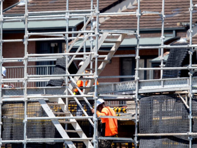 Worker assembling scaffolding on new social housing home unit block at 56-58 Beane St. Gosford, Australia. March 1, 2021. Part of a building construction series.